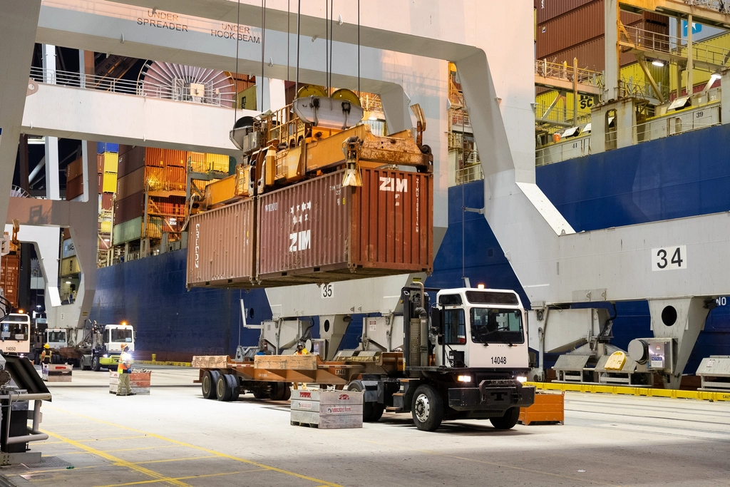 Crew loading shipping containers at a busy port